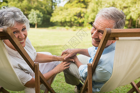 快乐的成熟情侣在镜头前微笑女士草原流金农村公园太阳椅晴天躺椅男人岁月图片