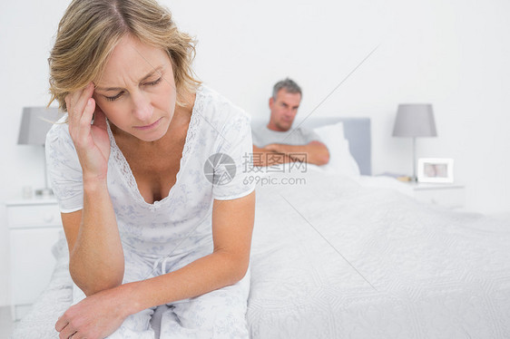 打架后坐在对面床边的一对不高兴的夫妇图片