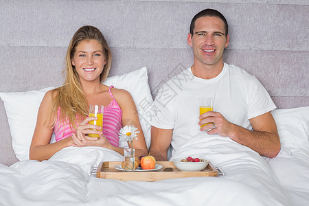 快乐的年轻夫妇在床上吃早餐金发房子头发男性谷物托盘卧室公寓感情睡衣图片