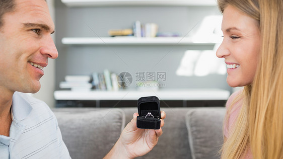 快乐男人在沙发上向女朋友求婚图片