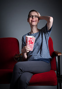 演播室30次拍摄的有吸引力的caucasian女孩灰色微笑休闲服红色冒充女性爆米花背景剧院歌剧图片