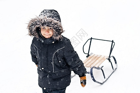 穿冬西装的年轻男孩 拉起雪橇活动手套孩子外套季节儿子运动闲暇情绪童年图片