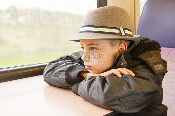 男孩坐在火车上 望着窗外旅游骑术速度损失运输孩子们帽子思维交通孩子图片
