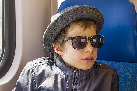 戴太阳眼镜的帅帅男孩坐火车太阳镜青少年旅游思维孩子童年速度损失铁路交通图片