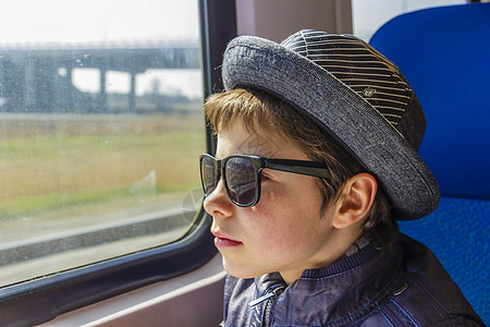 戴太阳眼镜的帅帅男孩坐火车思维损失窗户骑术记忆铁路孩子们运输旅游童年图片