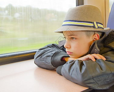 男孩坐在火车上 望着窗外运输损失青少年男生玻璃速度孩子们旅游思维童年图片