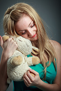 30岁有魅力的caucasian金发美女玩具熊吸引力女性绿色背景休闲服灰色羊肉腰部冒充图片