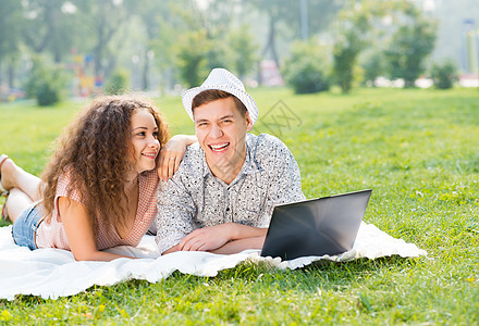 一对夫妇一起躺在公园里 带着笔记本电脑成年人男性女孩商业乐趣网络朋友们微笑夫妻生活图片