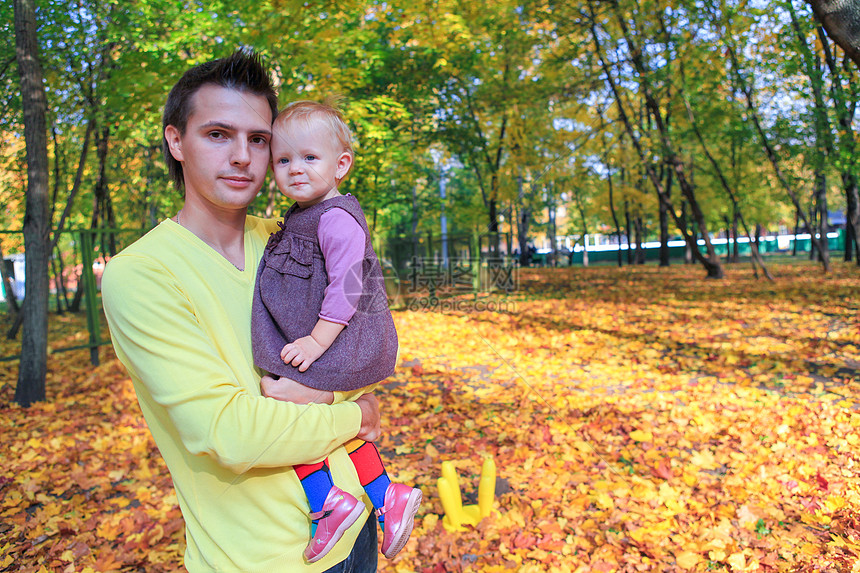年轻父亲与她可爱的小女儿在秋天公园户外行走图片