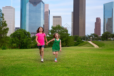 两个姐妹女孩朋友在城市的天线上手牵手跑来跑去金发跑步公园商业建筑学旅行地标家庭蓝色孩子们图片