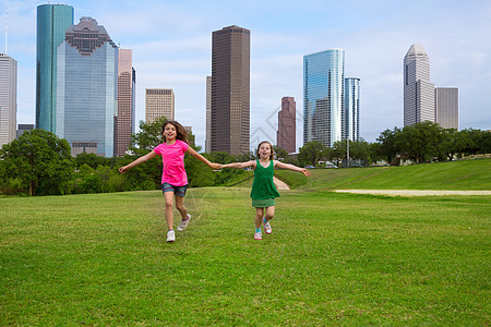 两个姐妹女孩朋友在城市的天线上手牵手跑来跑去旅行草地地标家庭高楼朋友们孩子们建筑物办公室跑步图片