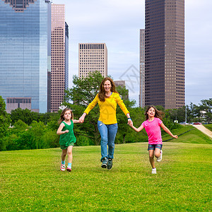 母亲和女儿们在城市天线上举手走路地标家庭建筑学蓝色公园女孩们姐妹旅行办公室金发图片