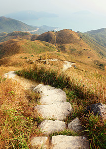 在山上徒步旅行小路土地石头路径草地场地岩石芦苇人行道天空图片