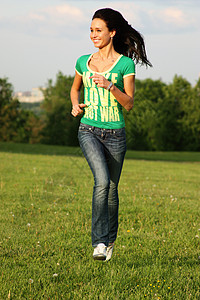穿蓝牛仔裤和囚衣的年轻妇女空气细胞衬衫蓝色公园快乐黑发腰部肩膀跑步图片