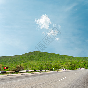 通向月云下山顶地平线的沥青柏油路图片