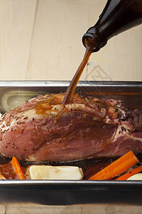 在烤猪肉上倒啤酒瓶子洋葱烘烤烹饪盘子棕色食物图片