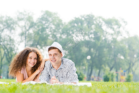一对夫妇躺在夏天公园的草地上成人乐趣家庭女性男人微笑女士青年夫妻幸福图片