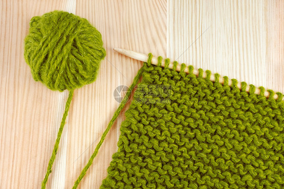 在编织针头上缝绿色羊毛和围衣针图片