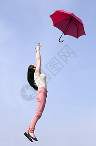妇女用伞跳跃长发喜悦女子红色飞行投掷遮阳棚风暴女孩快乐图片