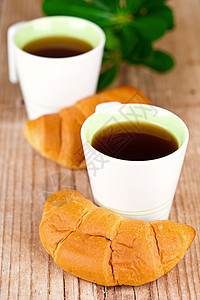 两杯茶和两杯新鲜的羊角面包甜点脆皮茶点早餐木头食物小吃叶子杯子液体图片