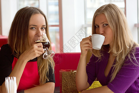 两个女孩在自助餐厅喝咖啡微笑女性快乐餐厅女孩们城市团体桌子乐趣享受图片