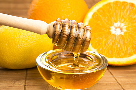 含柠檬和橙子水果的新鲜蜂蜜金子餐具甜点液体漏勺甜食玻璃生活方式木头黄色图片