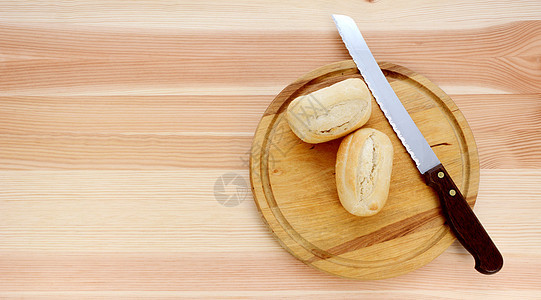两个面包卷 一把刀和木制板图片