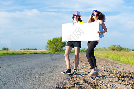两名年轻女性站在空白的横幅上站着季节游客远足者旅游冒险天空自由纸板旅行木板图片