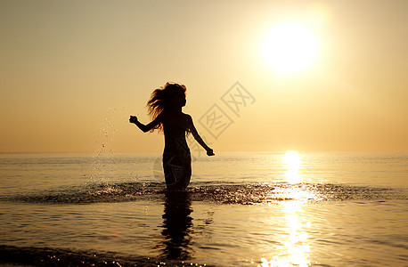 在沙滩上欢乐快乐女性反射头发日落运动动力学海洋跑步海浪阳光图片