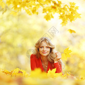 女人躺在秋叶上快乐森林叶子女性幸福乐趣女孩喜悦公园微笑图片