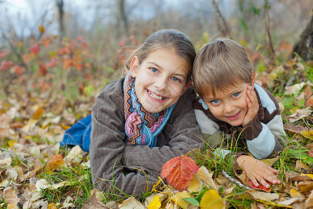 秋天公园的孩子树叶太阳男生乐趣青少年晴天季节女孩蓝色围巾图片