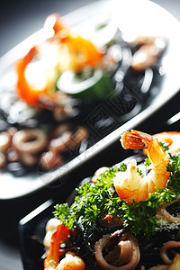 黑意面加海鲜餐厅面条胡椒食物桌子贝类墨水盘子蔬菜午餐图片