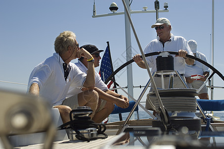 乘游艇对着清蓝的天空在船舵上说话的水手们图片
