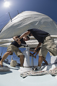 在游艇上操作风扇的机组人员低角度视角冒险船夫年轻人中年休闲起重成年人绳索竞赛闲暇背景图片