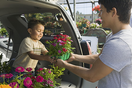 父亲把花盆送给儿子 在植物苗圃的一辆小货车后面图片