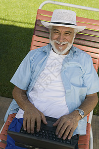坐在草坪椅子上的高级男子 使用笔记本电脑高端的观景肖像图片