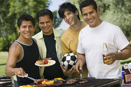 快乐的男性朋友在公园烧烤食物的肖像图片