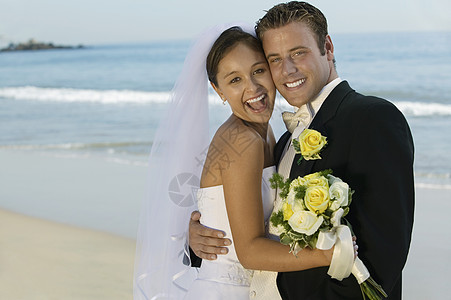 一个快乐的新娘和新郎在海滩上拥抱的肖像图片