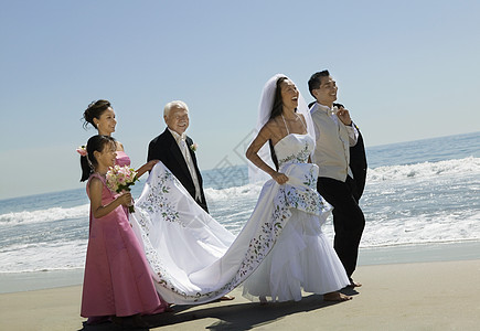 新娘和Groom与家人一起在海滩上散步图片