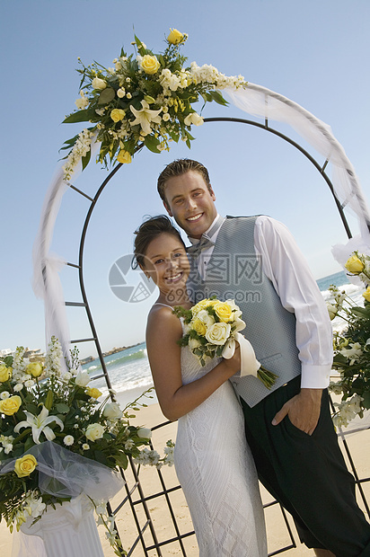 海滩大拱门下肖像的新娘和Groom海洋关系结婚正装表情连衣裙婚礼服风格玫瑰新郎图片