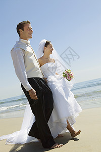在海滩上散步的新娘和Groom图片