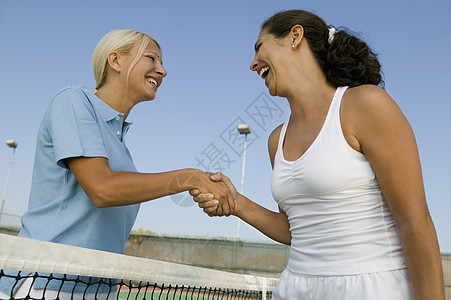 两个女性网球玩家在网球法庭上 握着网球场净低角度视图图片