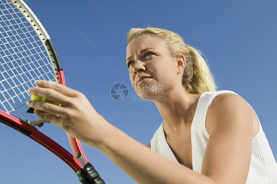 一位女性网球运动员的低角度视角 该女网球手准备在清蓝天空中服务爆头活动生活成年人中年娱乐竞技摄影器材消遣图片