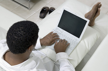 使用膝上型电脑高角度视图在沙发上仰卧办公计算机用户中年男性人士成年人职业硬件商业图片