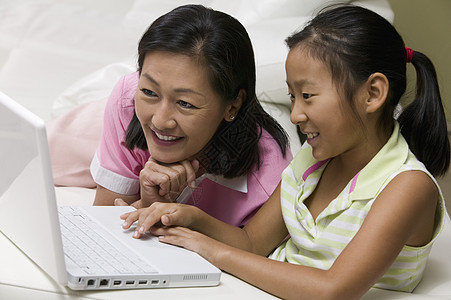 母亲和女儿在客厅使用笔记本电脑享受妈妈家庭生活幸福计算机孩子们用户两个人成年人团结图片