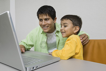 父亲和儿子在书桌 用笔记本电脑关门图片