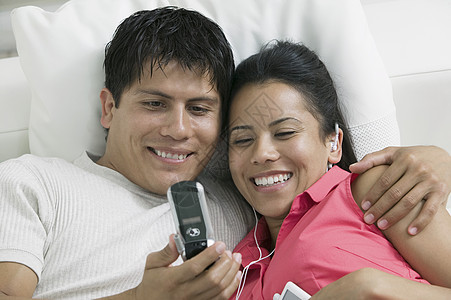 坐在沙发上看手机照片的一对幸福情侣的紧贴镜头图片