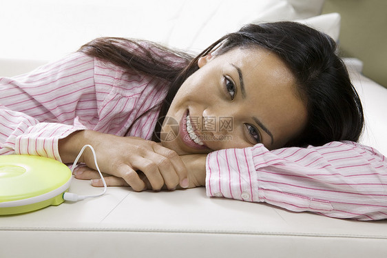 在沙发上躺着的女人 由便携式CD播放器肖像图片