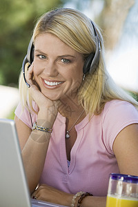 妇女使用膝上型电脑穿戴电话耳机图片