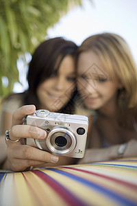 两名年轻妇女在后院看数码相机照片 关注照相机地面景点 (以摄像头地面视图为主)图片